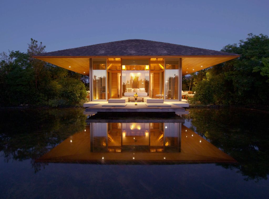 Exklusive Villa im Amanyara Hotel bei Dämmerung mit Lichtreflexionen auf dem Wasser.