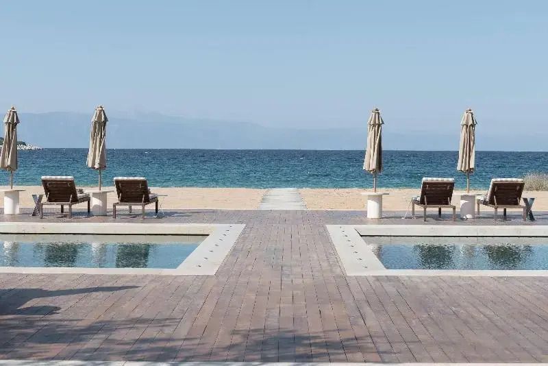 Luxuriöser Strandbereich mit Liegen und Blick auf das Meer am Hotel Amanzoe