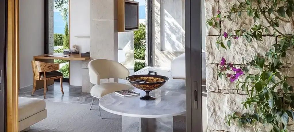 Helles und elegantes Zimmer mit Marmortisch und Blick auf mediterrane Vegetation