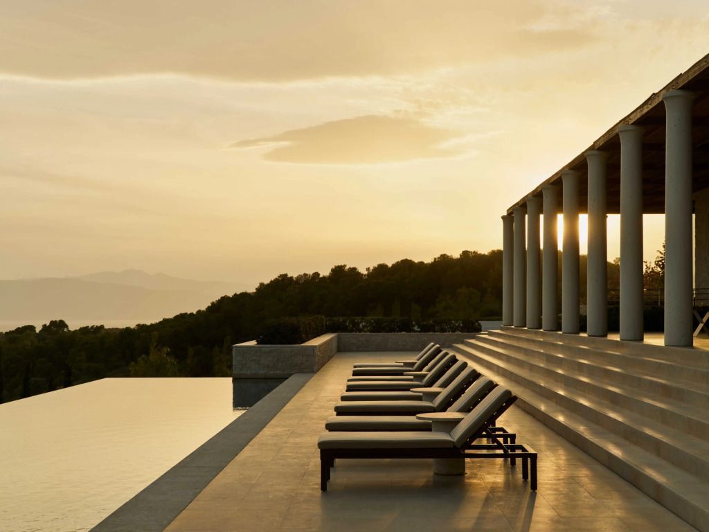 Infinity-Pool mit Liegestühlen und Blick auf die Landschaft bei Sonnenuntergang