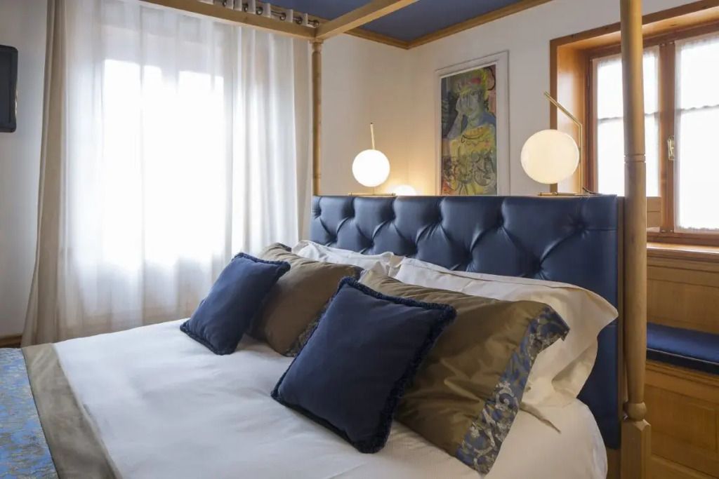 Doppelzimmer mit blauem Kopfende und stilvollen Kissen in einem eleganten Ambiente