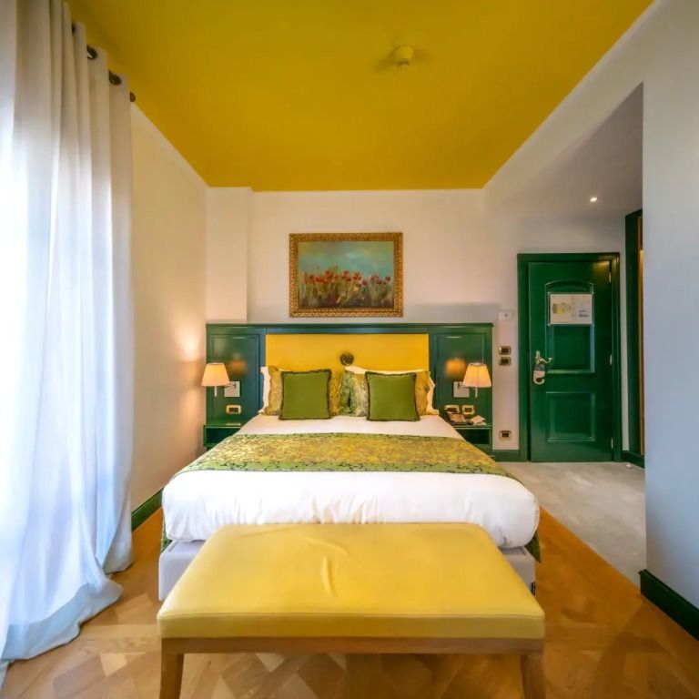 Lebhaftes Zimmer mit gelben und grünen Akzenten sowie einer passenden Bank am Bettende