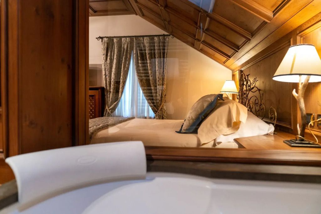 Blick auf das Bett durch Fenster vom Jacuzzi im Hotel Ambra Cortina