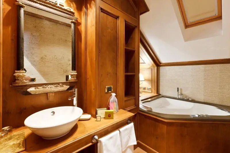 Elegantes Badezimmer mit Waschtisch und Spiegel neben Jacuzzi im Hotel Ambra Cortina