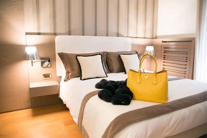 Stilvolles Zimmer mit Doppelbett und eleganter gelber Tasche auf der Bettdecke