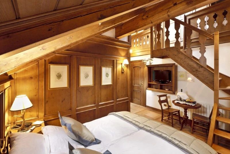 Luxuriöses Zimmer mit Dachschräge, Holzwänden und kleiner Sitzecke