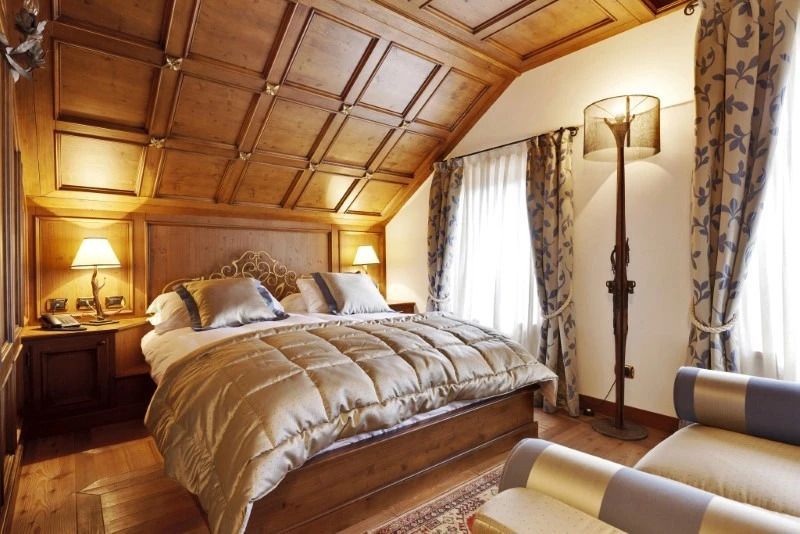 Gemütliches Doppelzimmer mit Holzdecke und elegantem Bett.