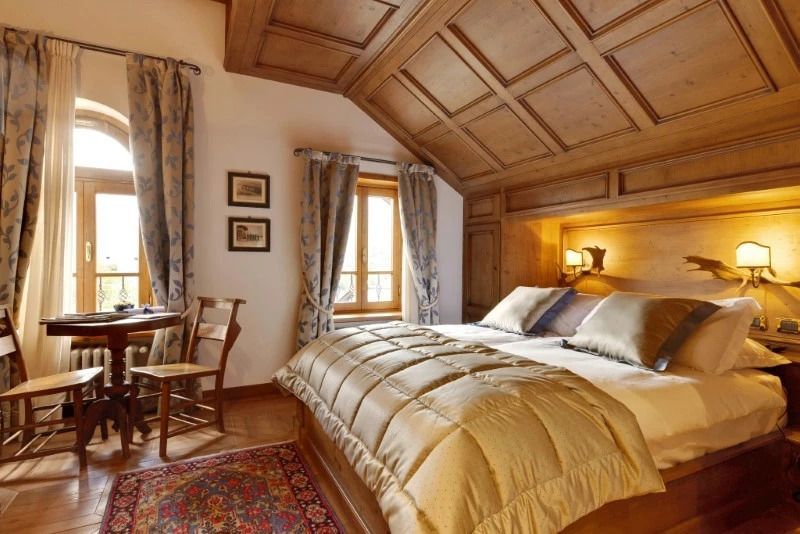 Doppelzimmer mit geblümter Gardine und Holzbalkendecke.