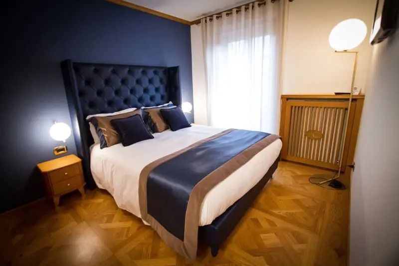 Moderner Schlafbereich mit blauem Kopfteil und Holzdetails in einem Hotelzimmer