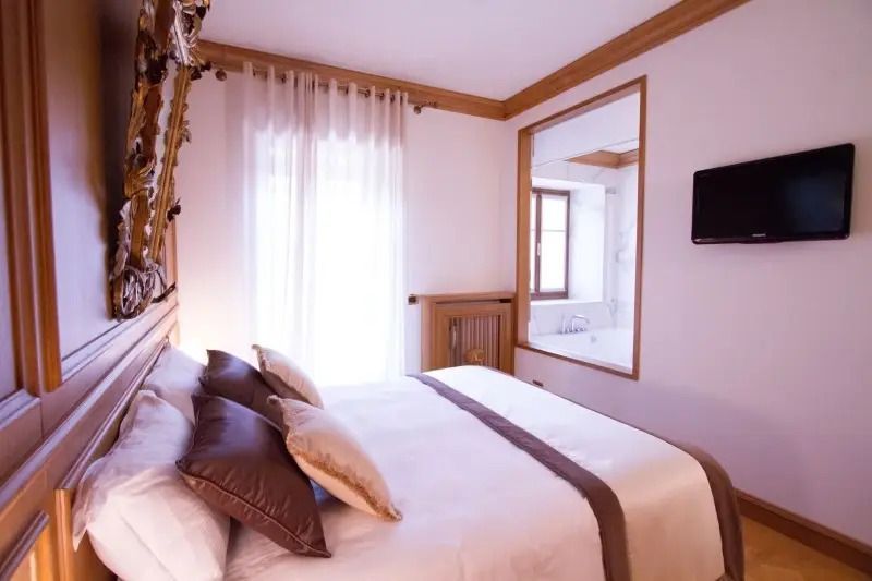 Helles Hotelzimmer mit klassischem Dekor und großem Spiegel an der Wand