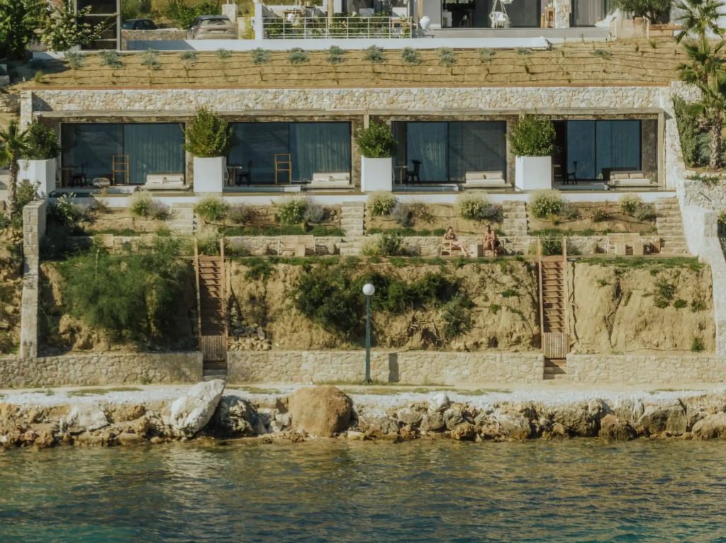 Außenansicht des Hotels mit Meer im Vordergrund und terrassierter Landschaft