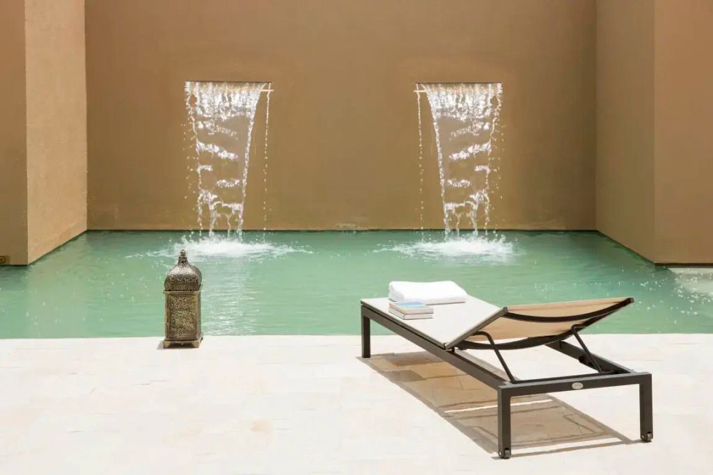 Privater Poolbereich mit Sonnenliegen und eleganten Wasserfällen
