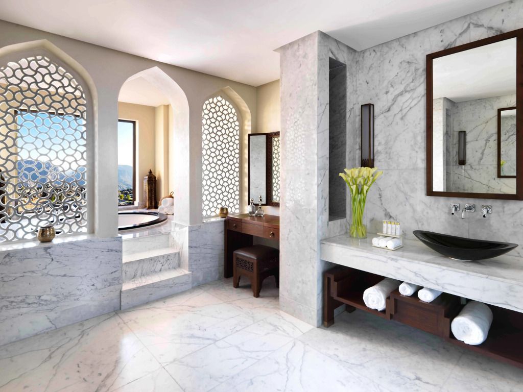 Luxuriöses Badezimmer aus Marmor mit Badewanne und dekorativen Fensterrosetten