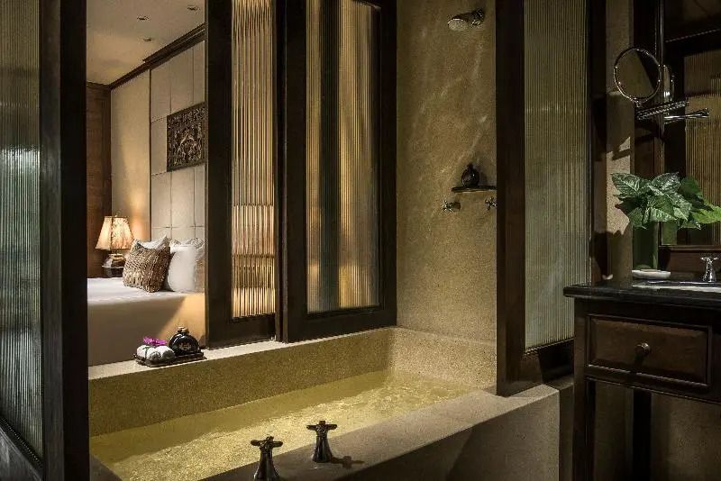 Elegantes Badezimmer mit eingelassener Wanne und Sicht ins Schlafzimmer