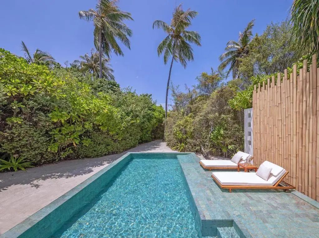 Privater Poolsonnendeck mit Liegen und tropischer Vegetation
