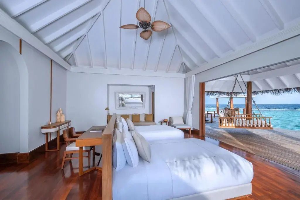 Helles Schlafzimmer mit zwei Betten in Overwater-Villa mit Blick auf das Meer.
