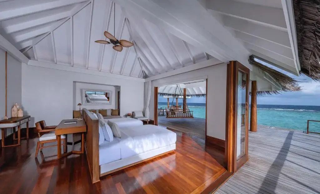 Offene Schlafzimmersuite in einer Overwater-Villa mit zwei Betten und Meerblick.