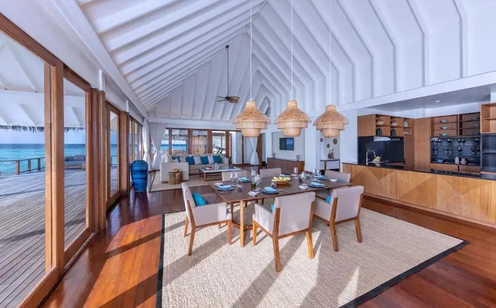 Großer Wohnbereich mit Esstisch in einer Overwater-Villa mit hoher Decke.