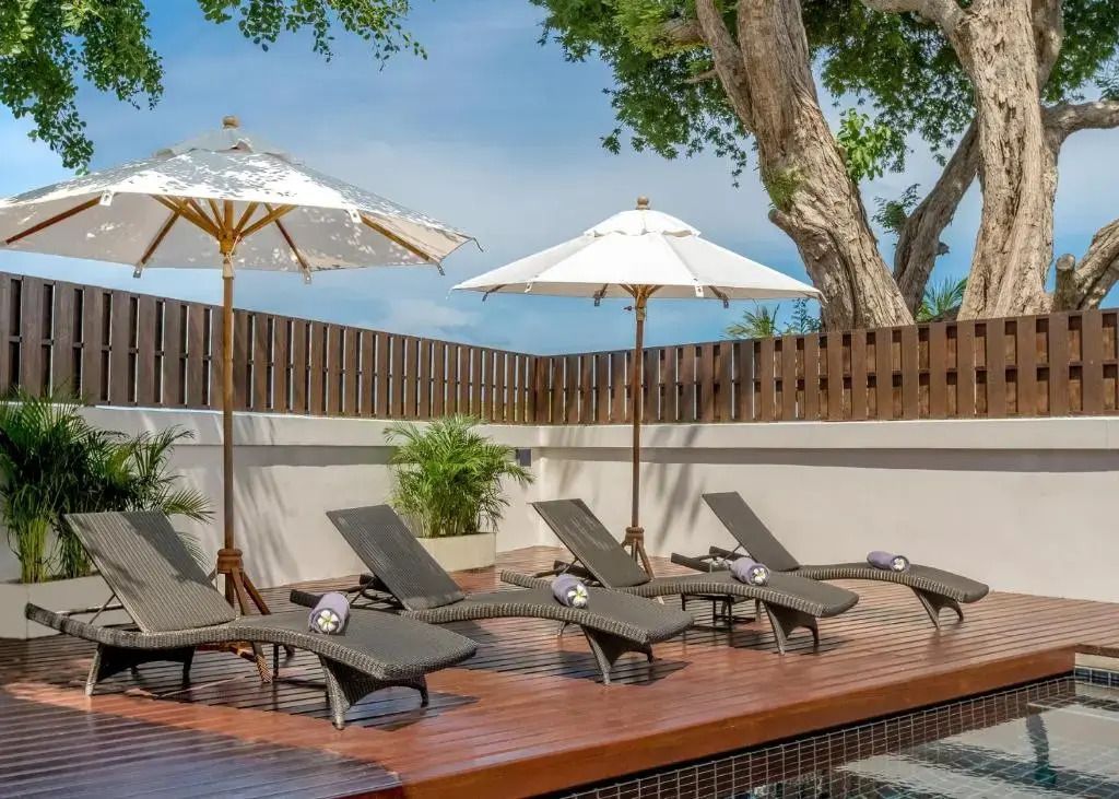 Sonnendeck mit Liegen und Sonnenschirmen neben einem privaten Pool.