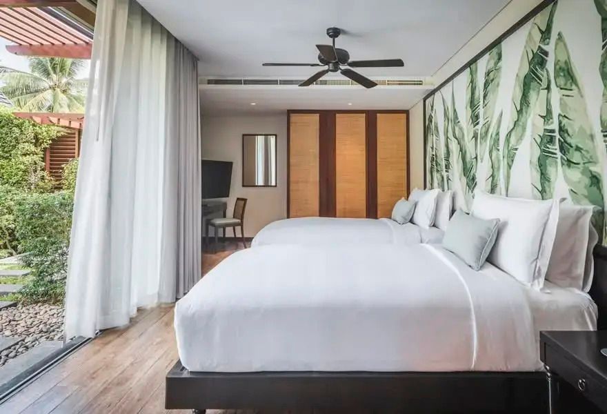 Elegantes Schlafzimmer mit zwei Betten und großen Fenstern im Anantara Mai Khao Phuket Villas