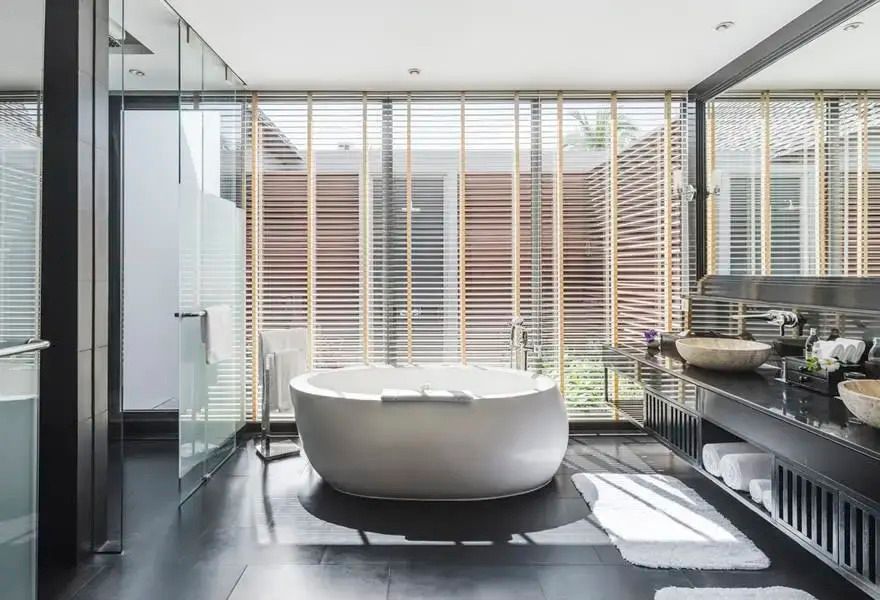 Modernes Badezimmer mit freistehender Badewanne und Holzlamellen am Fenster