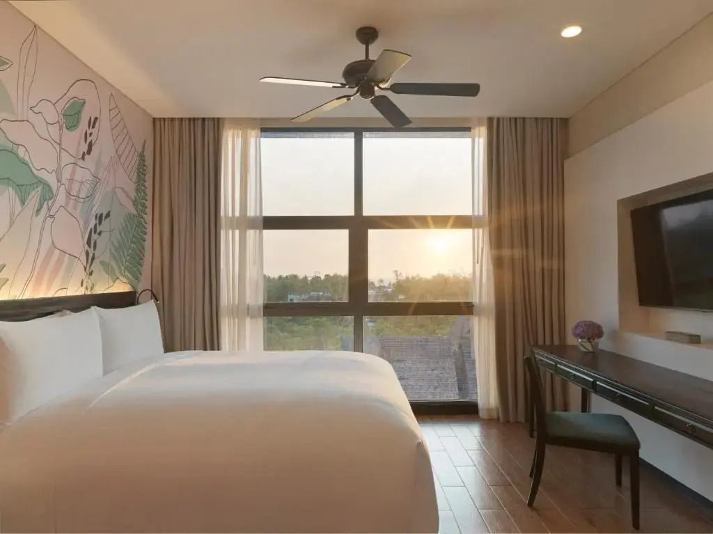 Helles Schlafzimmer mit Fensterfront und stilvoller Inneneinrichtung bei Sonnenuntergang