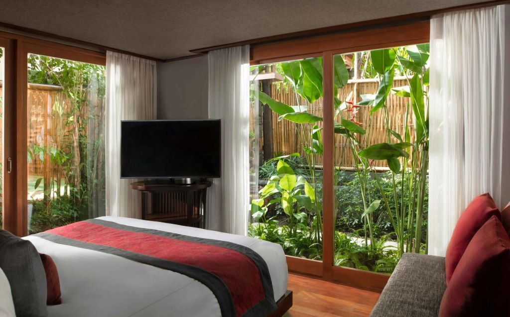 Schlafzimmer mit großen Fenstern und Blick auf üppiges Grün