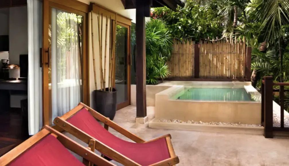 Private Terrasse mit Liegestühlen und kleinem Pool umgeben von Pflanzen