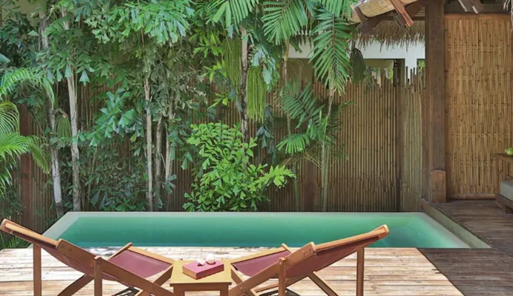 Zwei Liegestühle auf der Terrasse der Lagoon Doppel Pool Villa mit Blick auf tropische Vegetation