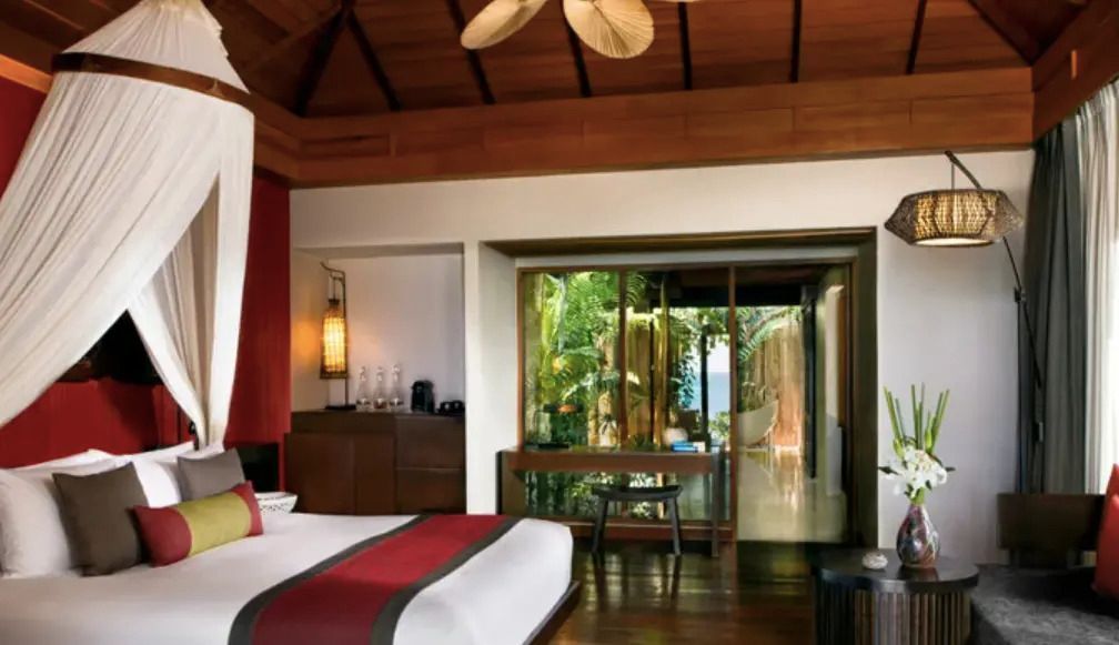 Elegantes Schlafzimmer mit gemütlichem Bett und Zugang zum tropischen Garten