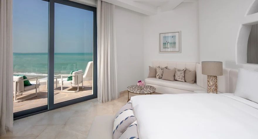 Helles Hotelzimmer mit Meerblick und Sitzbereich im Fira Doppelzimmer Anantara Santorini.