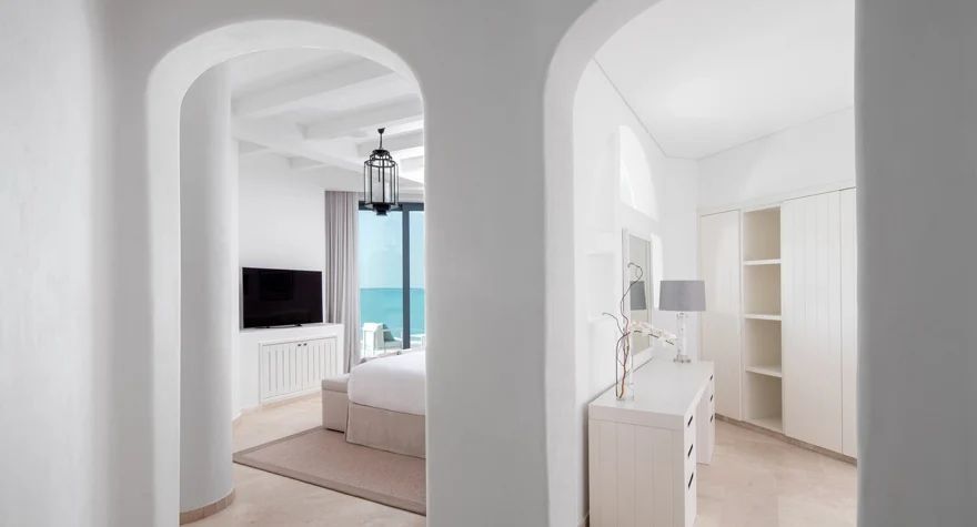 Zimmeransicht durch einen Bogen mit Blick auf das Meer und modernes Interieur.