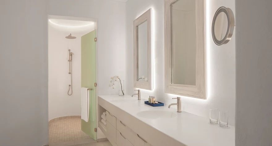 Geräumiges Badezimmer mit Doppelwaschbecken und beleuchteten Spiegeln in heller Umgebung.