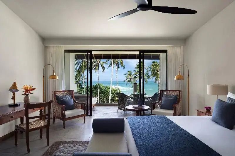 Geräumiges Hotelzimmer mit direktem Ausblick auf den Strand und Palmen