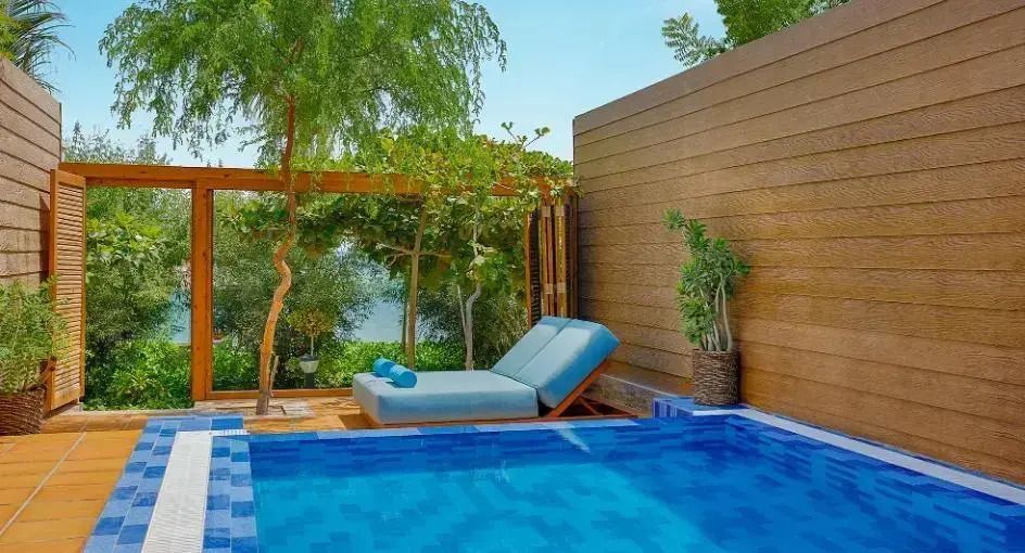 Privater Pool mit Liegestuhl und üppiger Vegetation
