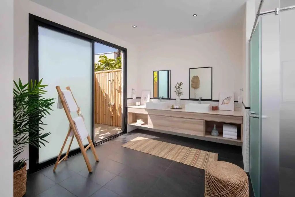 Modernes Badezimmer mit Doppelwaschbecken. Große Glaswand öffnet sich zum Garten.