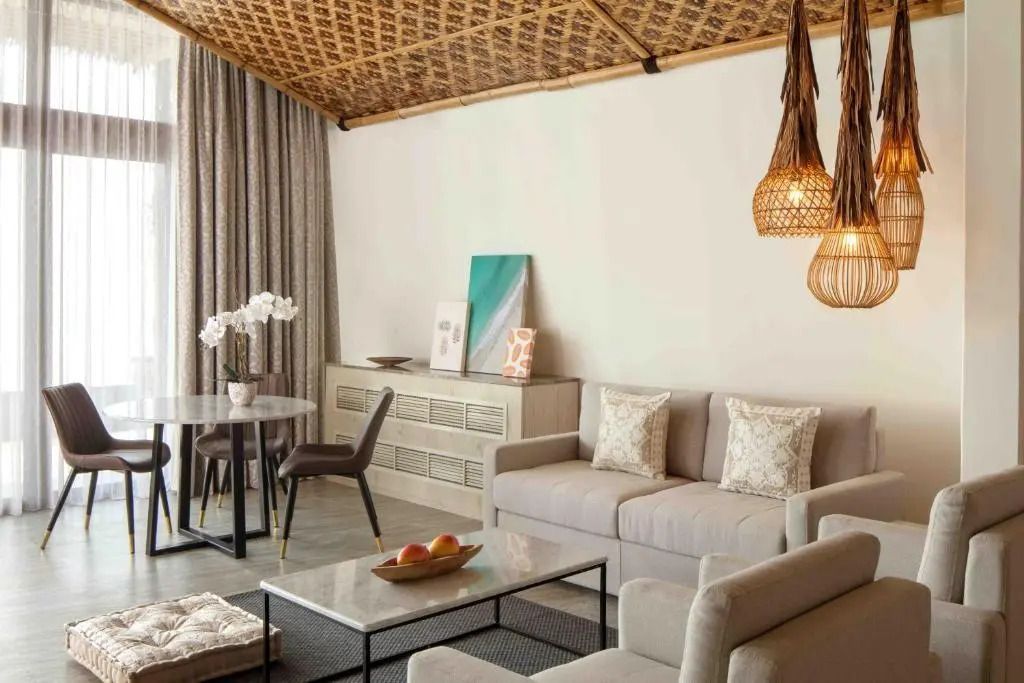 Elegantes Wohnzimmer mit Sofa und Esstisch. Dezente Dekoration und gewebte Decke.