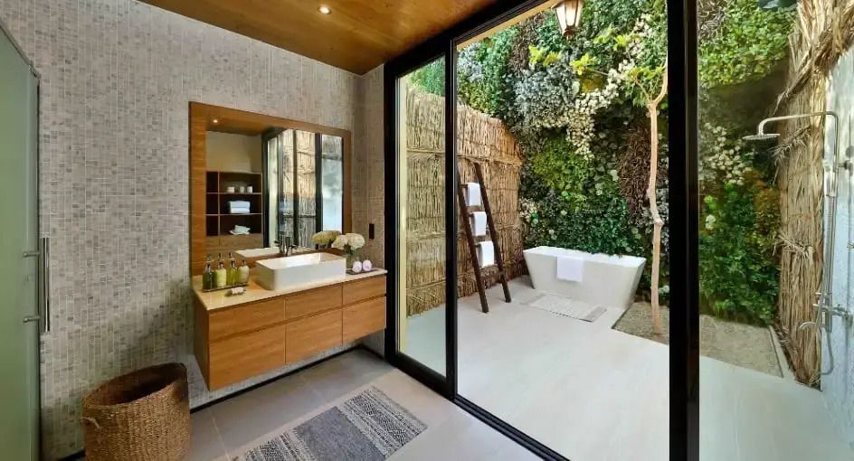 Luxuriöses Badezimmer mit Außenblick auf grüne Pflanzen und eleganter Badewanne.