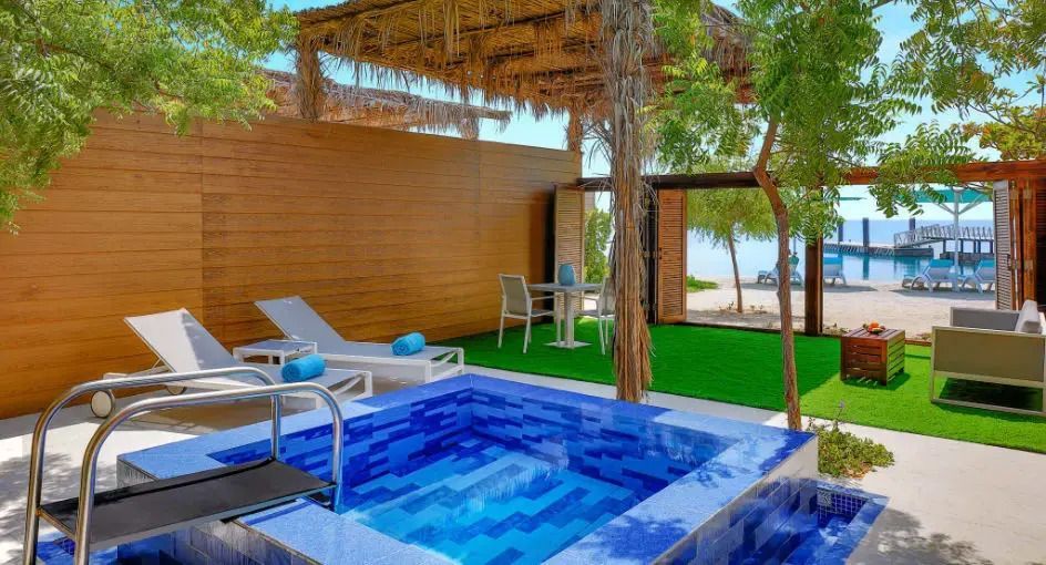 Privater Außenbereich mit kleinem Pool, Liegestühlen und Meerblick.