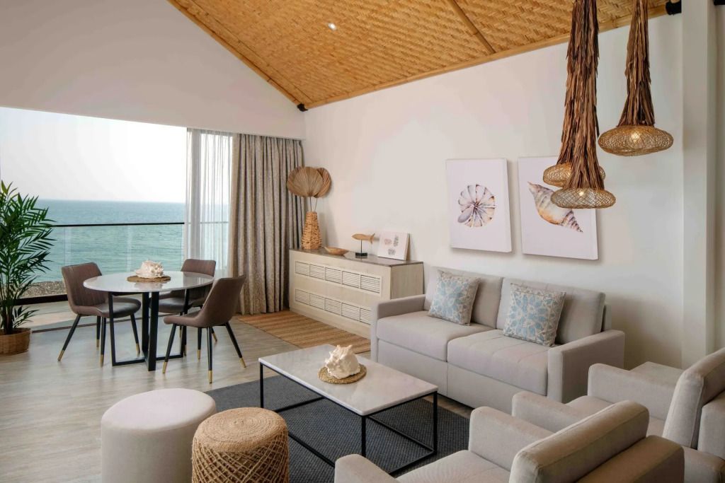 Wohnbereich einer Suite mit Meerblick, eleganter Einrichtung und Balkon.