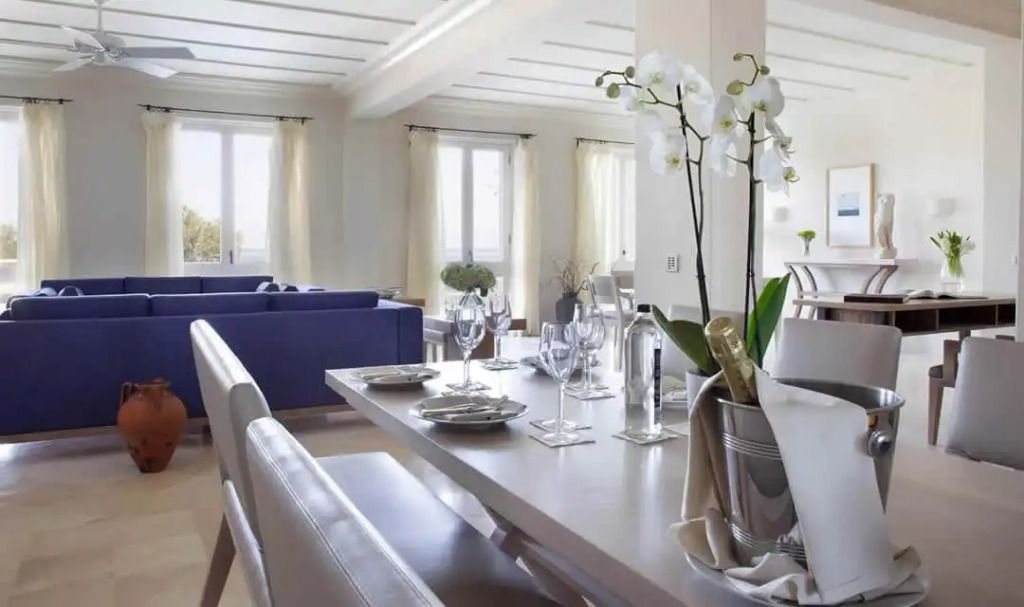 Elegantes Wohnzimmer mit Esstisch und blauen Sofas im Alcyone Residence