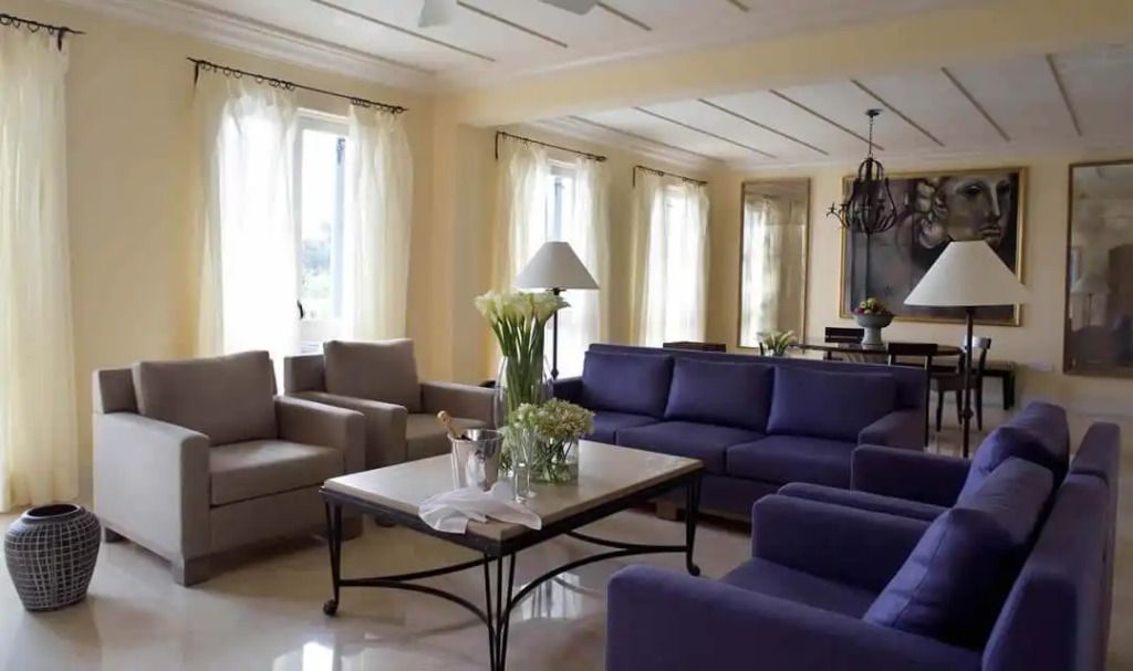 Geräumiges Wohnzimmer mit lila Sofas und großen Fenstern in der Alexandros Residence
