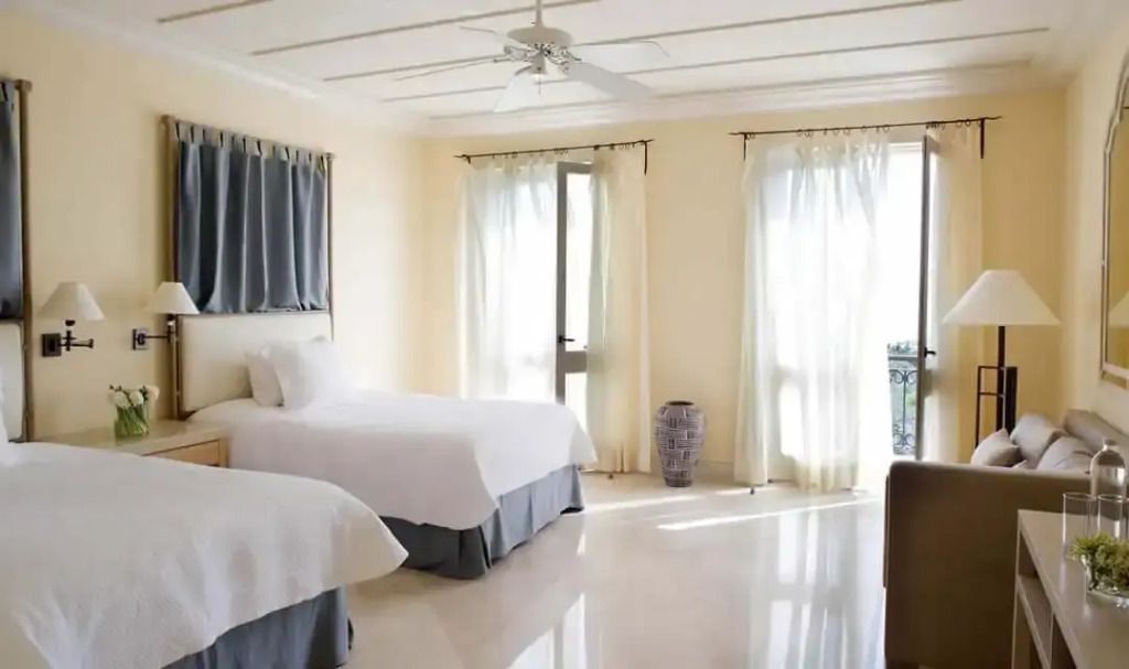 Zweibettzimmer mit großen Fenstern und Vorhängen in der Alexandros Residence