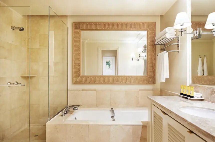 Luxuriöses Badezimmer mit großer Badewanne, großem Spiegel und eleganten Fliesen.