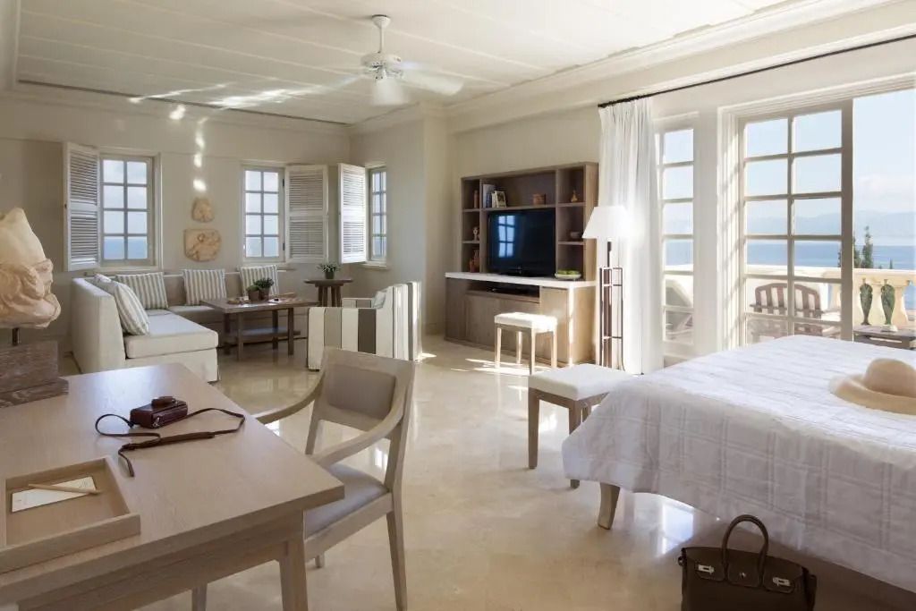 Helle Junior-Suite mit Doppelbett, Sitzbereich und TV vor großen Fenstern