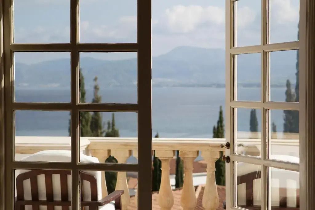 Balkonblick auf das blaue Meer und die Berge durch offene Fenster
