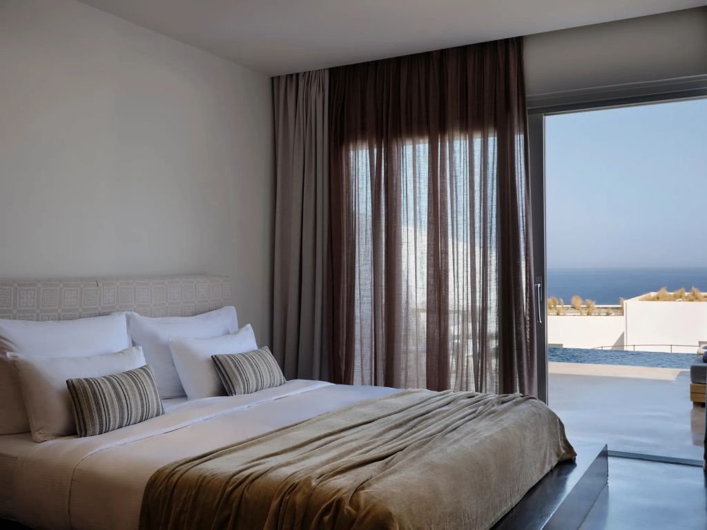 Schlafzimmer mit großem Fenster und Meerblick, in sanften Tönen gestaltet