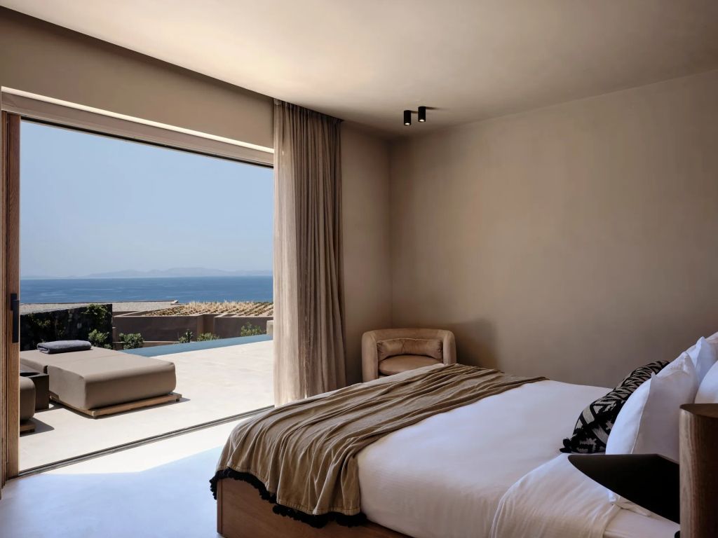 Helles Schlafzimmer mit Blick auf Terrasse und Meer im Hintergrund