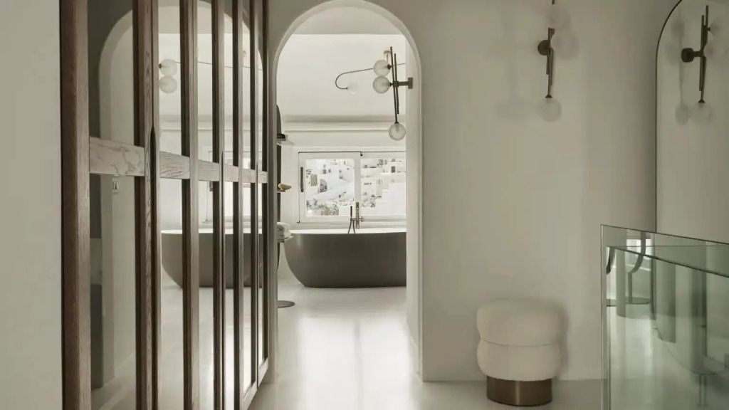 Blick ins Badezimmer mit freistehender Badewanne durch eleganten Bogen.