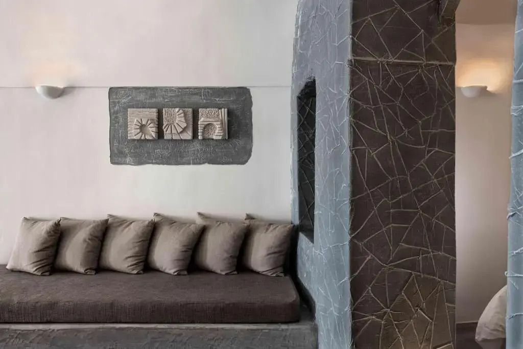 Elegante Sitzecke mit grauen Kissen und künstlerischen Wanddekorationen in der Suite.